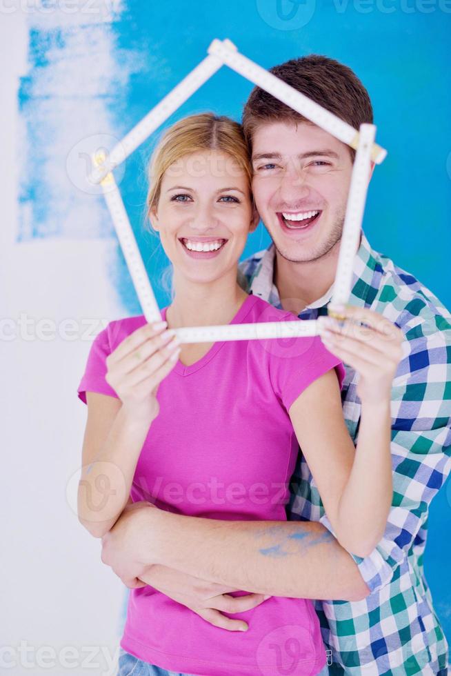 pareja feliz pintando una pared en su nuevo hogar foto