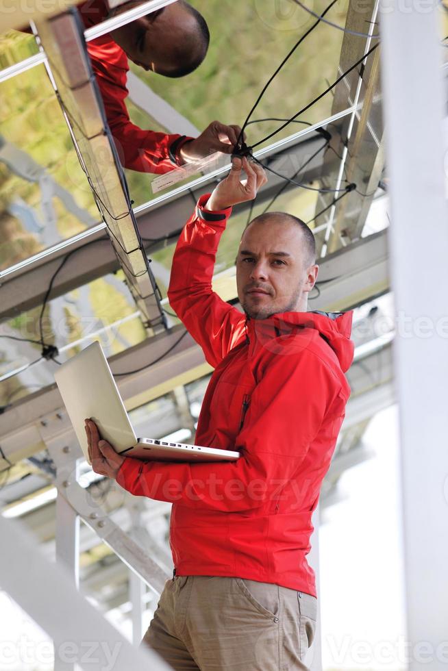 engineer using laptop at solar panels plant field photo