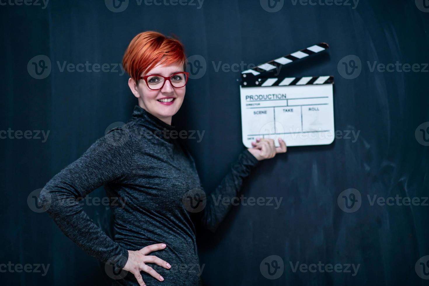 redhead woman holding movie clapper photo