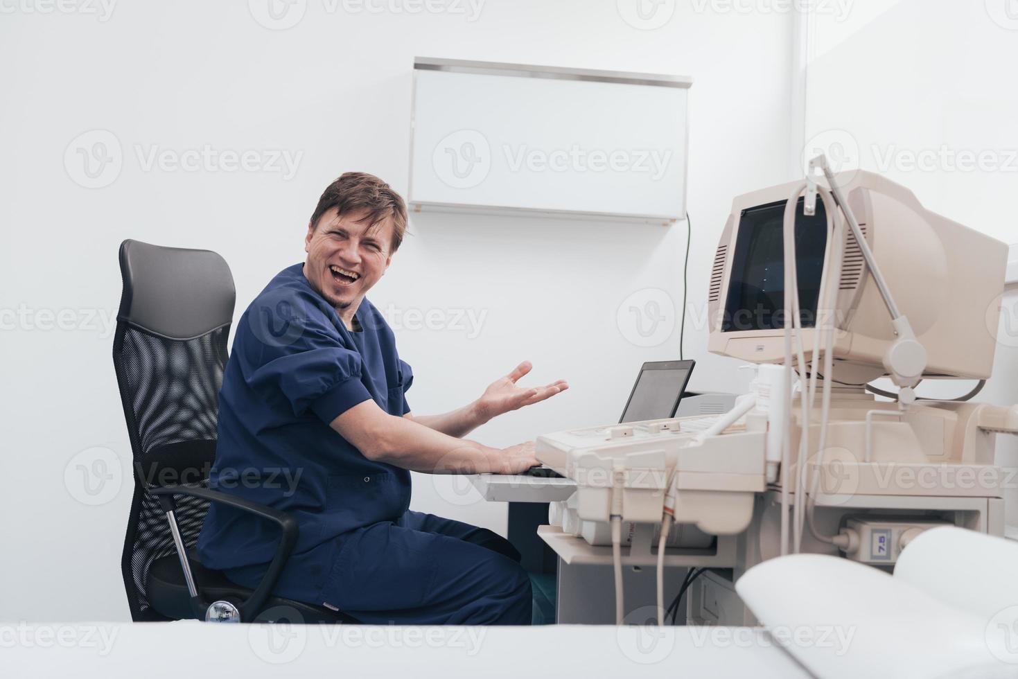 Orthopedist doctor examining X-ray picture at desk in clinic on laptop computer photo