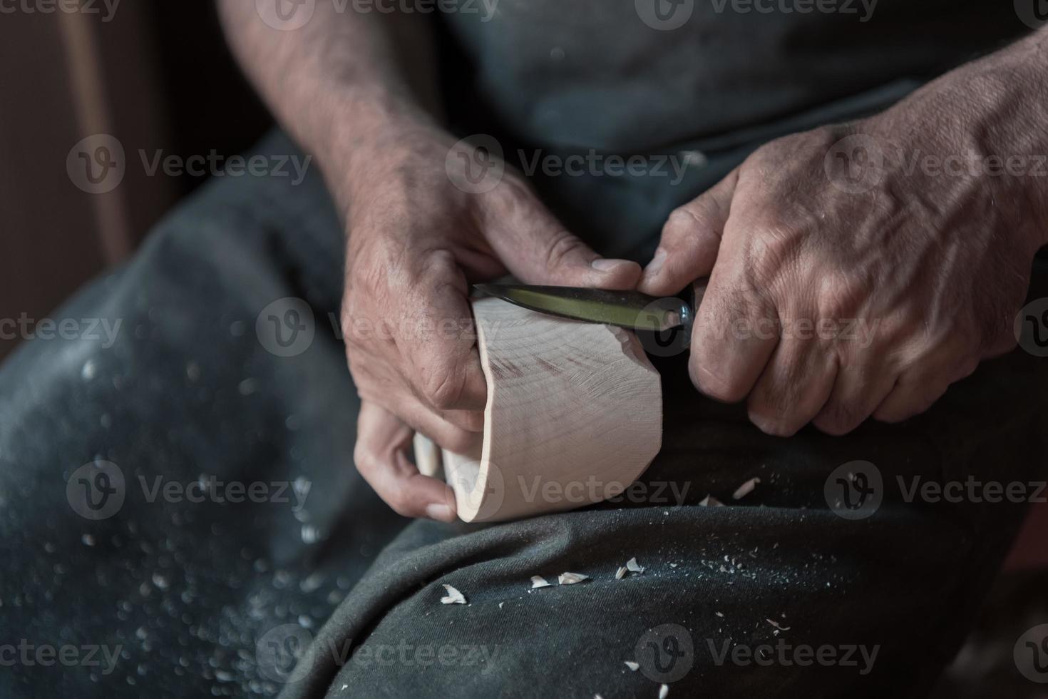 Hands carving cup from wood, working with chisel close up. Wooden workshop. Process of making wooden kitchenware photo