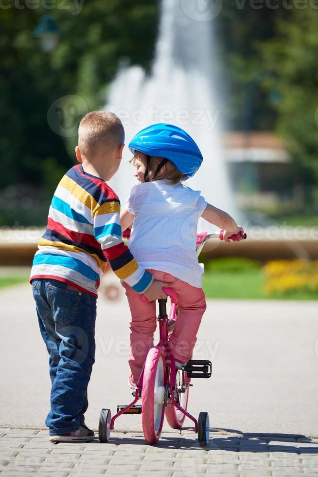 Boy and girl in park learning to ride a bike photo