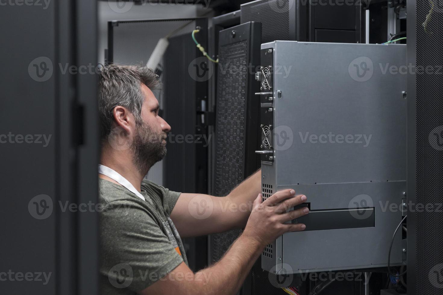 IT engineer working In the server room or data center The technician puts in a rack a new server of corporate business mainframe supercomputer or cryptocurrency mining farm. photo
