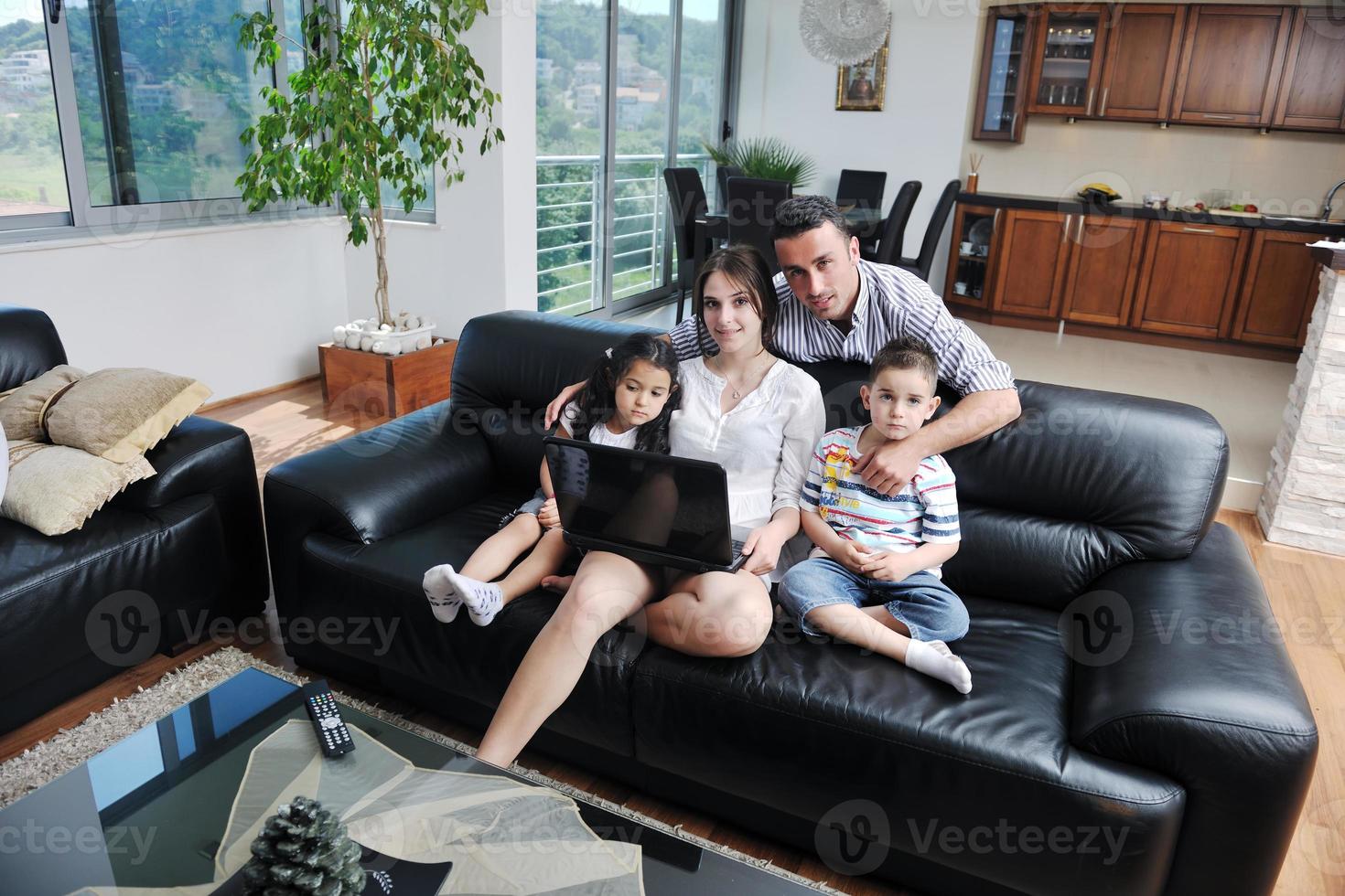 familia joven feliz divertirse y trabajar en la computadora portátil en casa foto