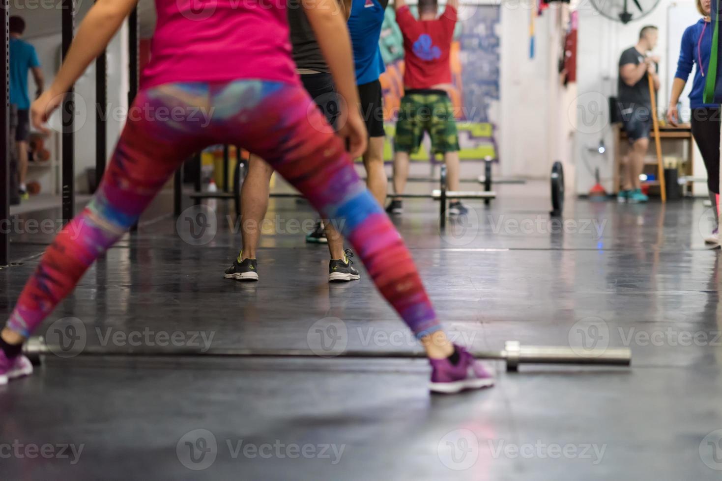 a group of people exercise with an empty bar photo