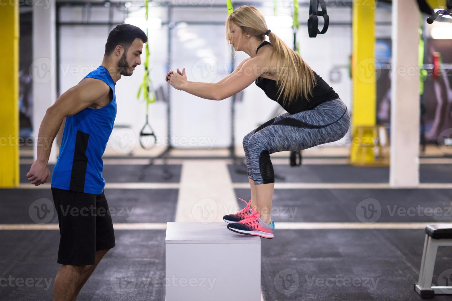 woman working out with personal trainer jumping on fit box photo