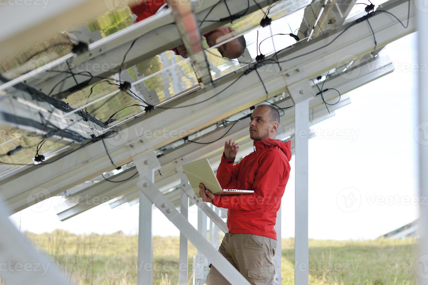 engineer using laptop at solar panels plant field photo