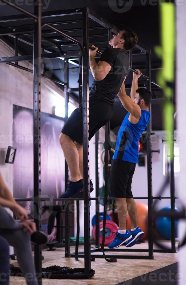 atletas jóvenes haciendo pull ups en la barra horizontal foto