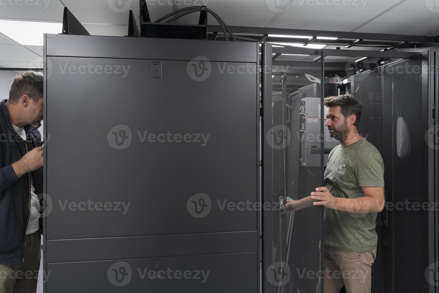 Technicians team updating hardware inspecting system performance in super computer server room or cryptocurrency mining farm. photo