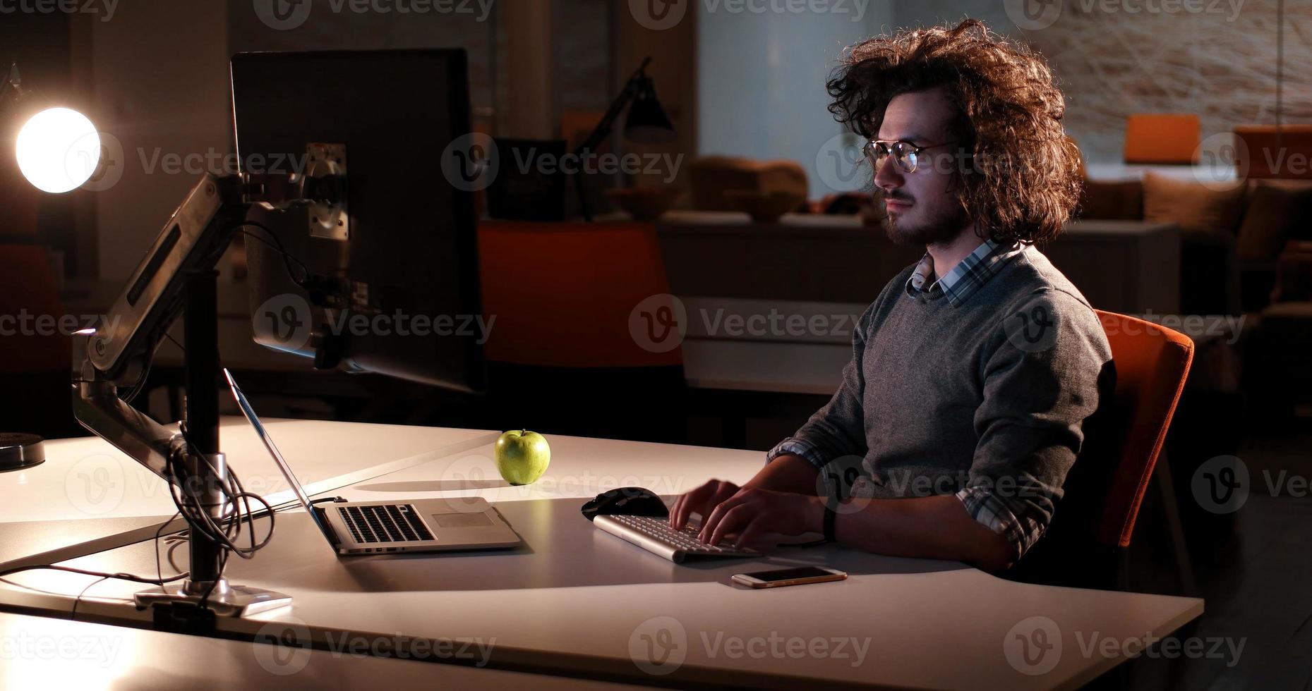 man working on computer in dark office photo