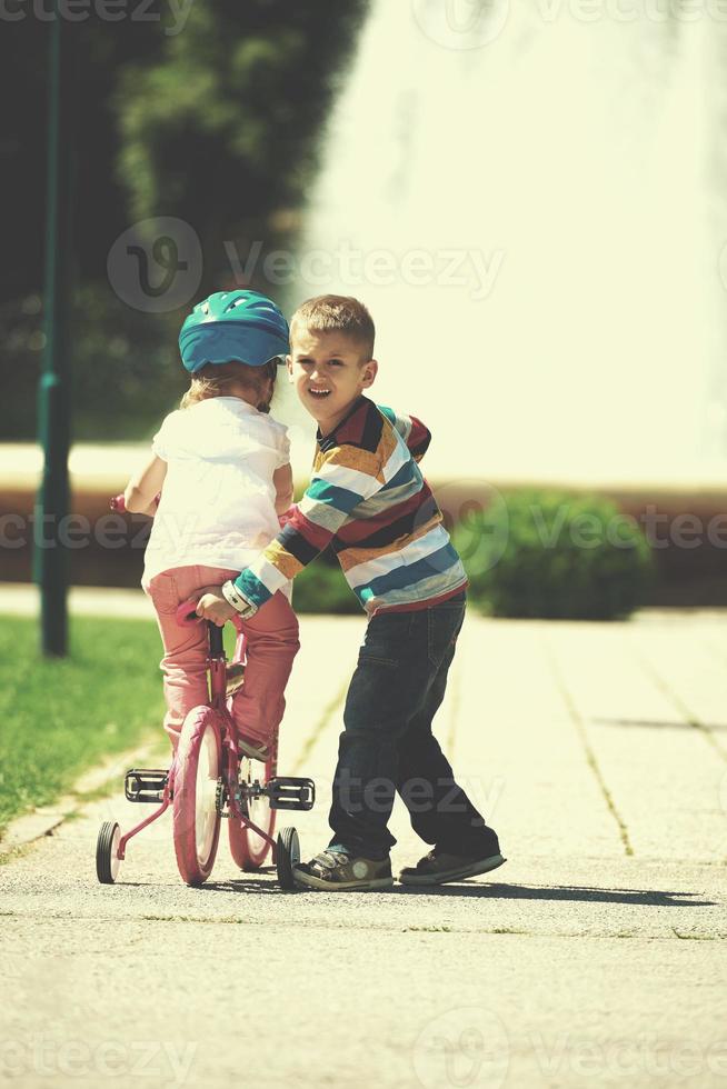 Boy and girl in park learning to ride a bike photo