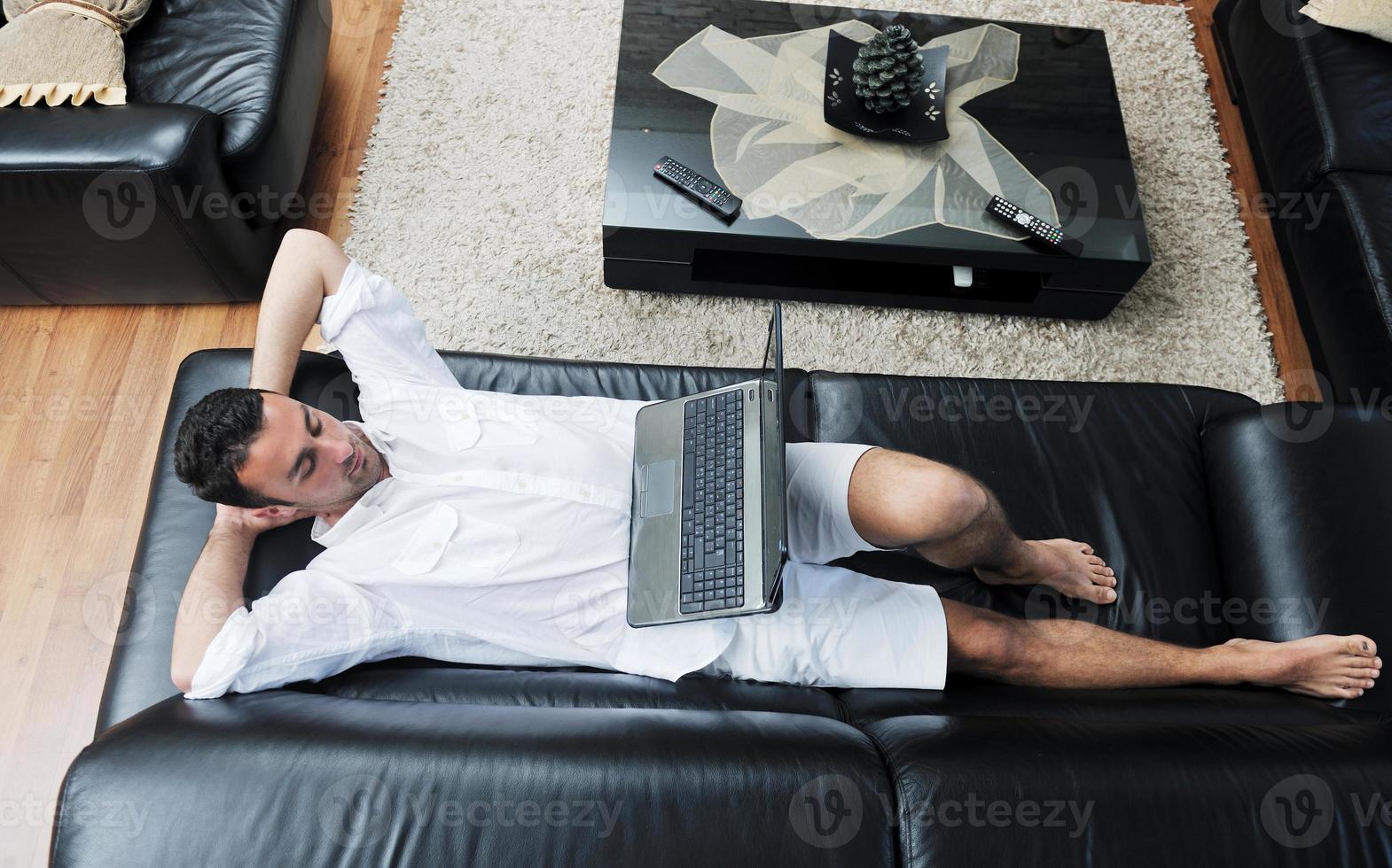 Portrait of a relaxed young guy using laptop at home photo