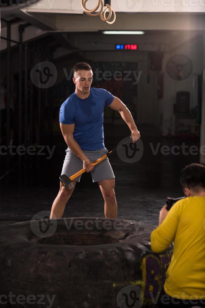 man workout with hammer and tractor tire photo