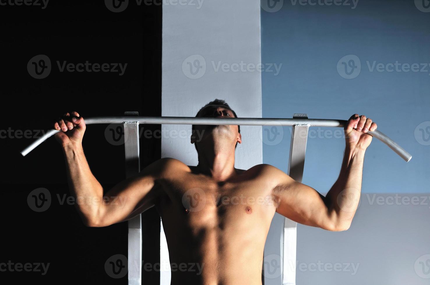 young man with strong arms working out in gym photo