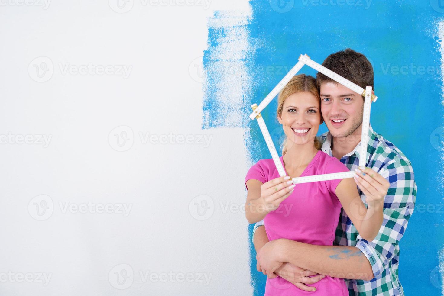 pareja feliz pintando una pared en su nuevo hogar foto