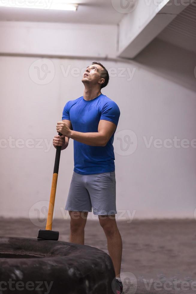 entrenamiento de hombre con martillo y neumático de tractor foto