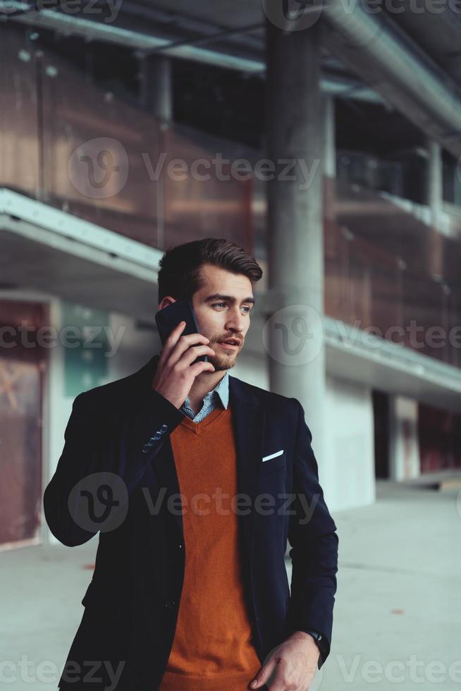 businessman architect using a smartphone while overseeing the construction site photo