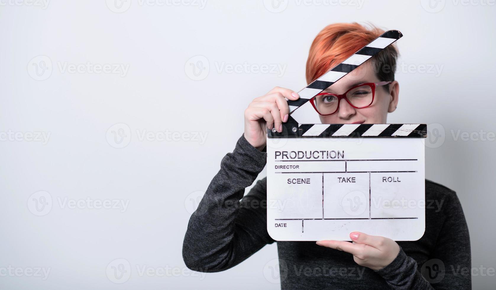 Mujer pelirroja sosteniendo badajo de película sobre fondo blanco. foto