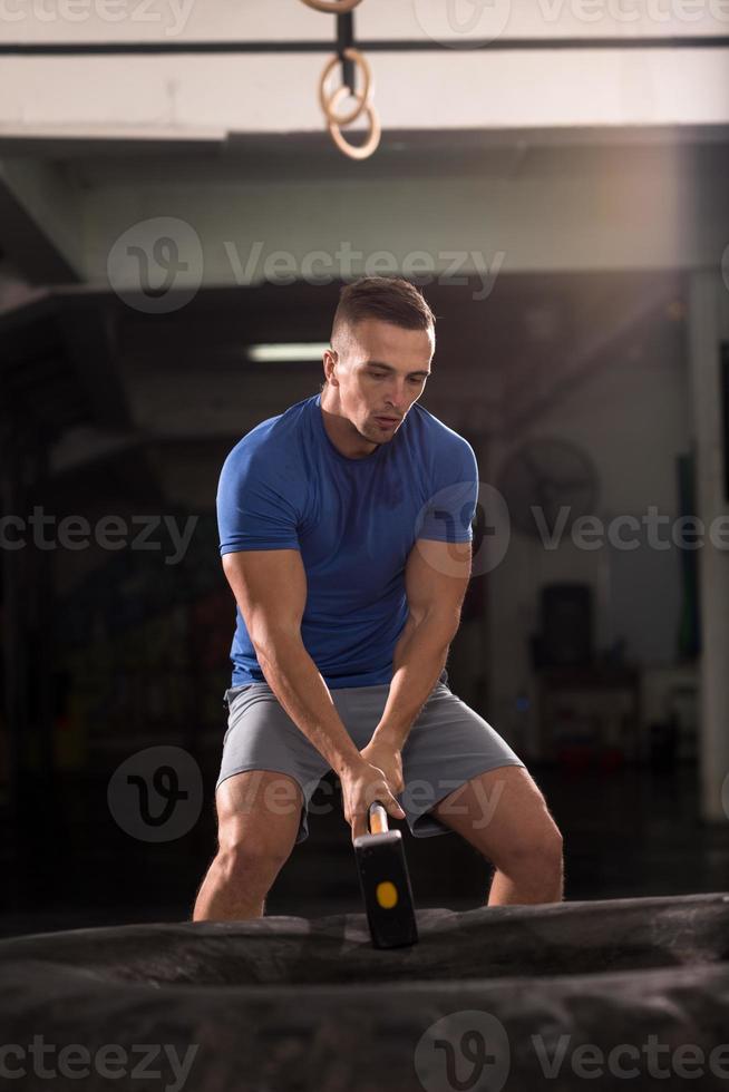 man workout with hammer and tractor tire photo