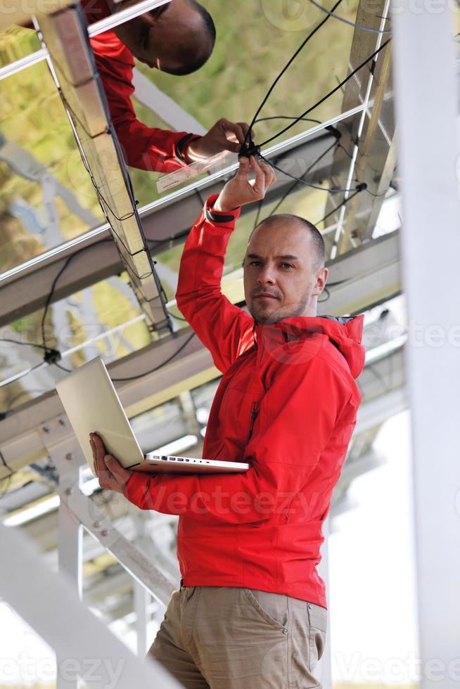 engineer using laptop at solar panels plant field photo