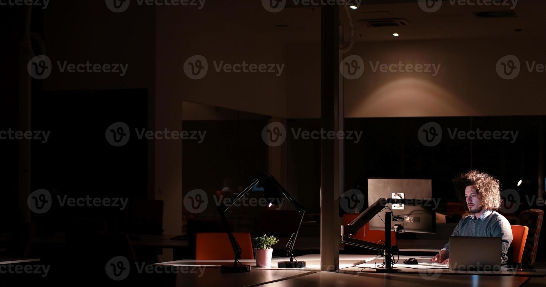 man working on computer in dark office photo
