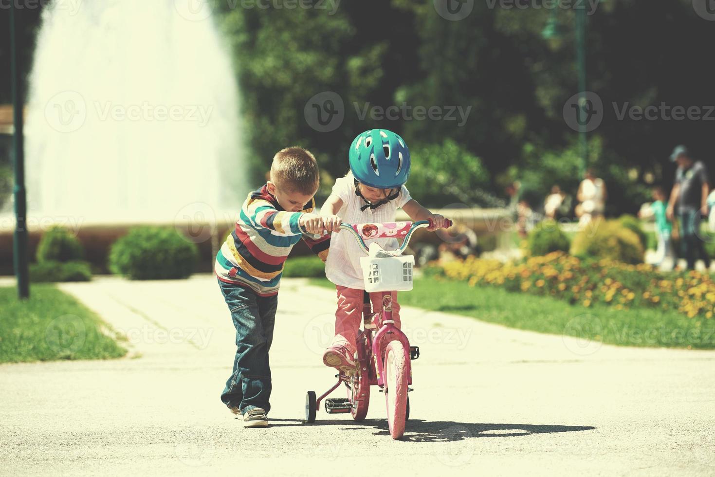 Boy and girl in park learning to ride a bike photo