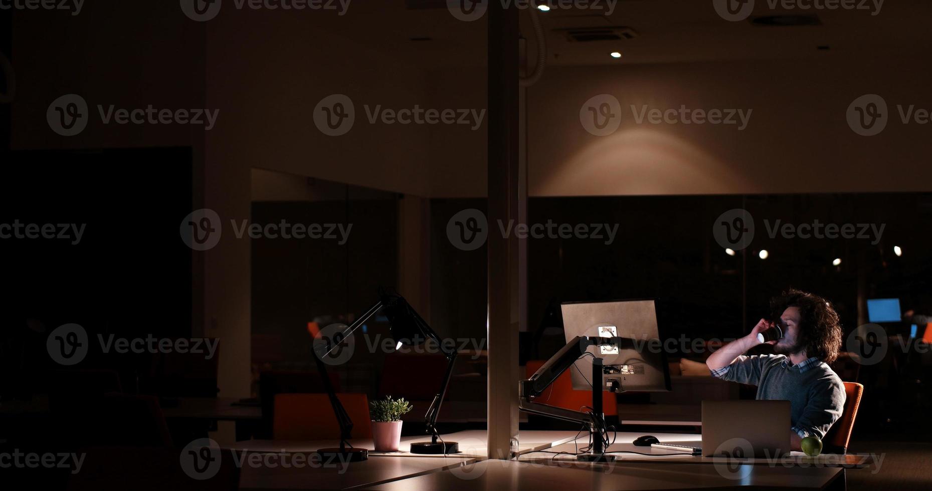 hombre trabajando en una computadora en una oficina oscura foto