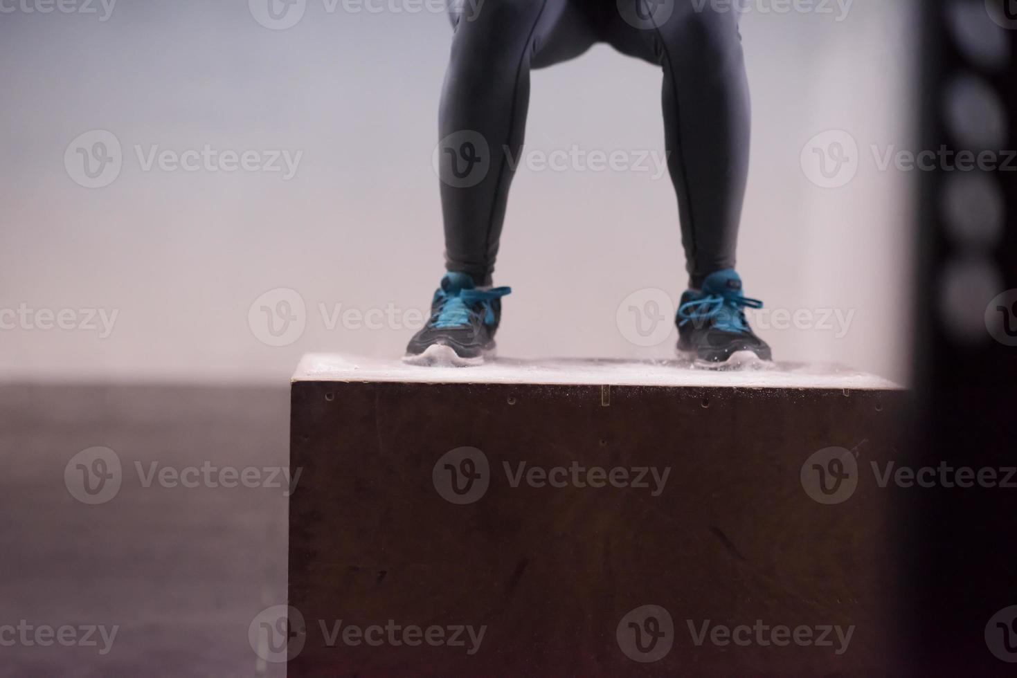 black woman is performing box jumps at gym photo