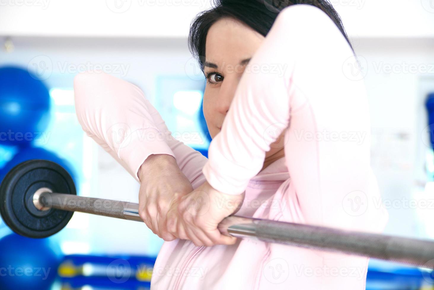 .a young woman weightlifting at gym photo