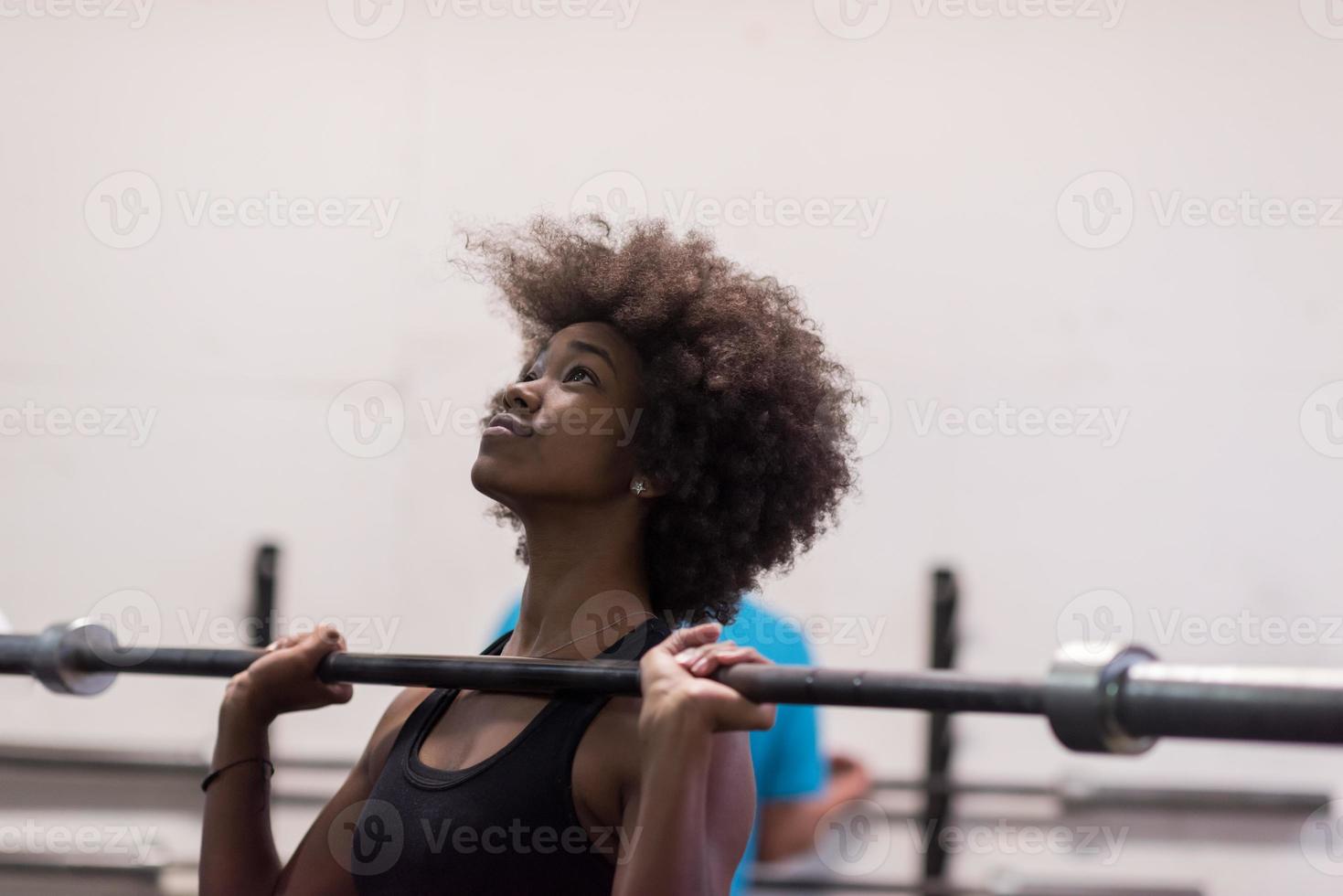 black woman lifting empty bar photo