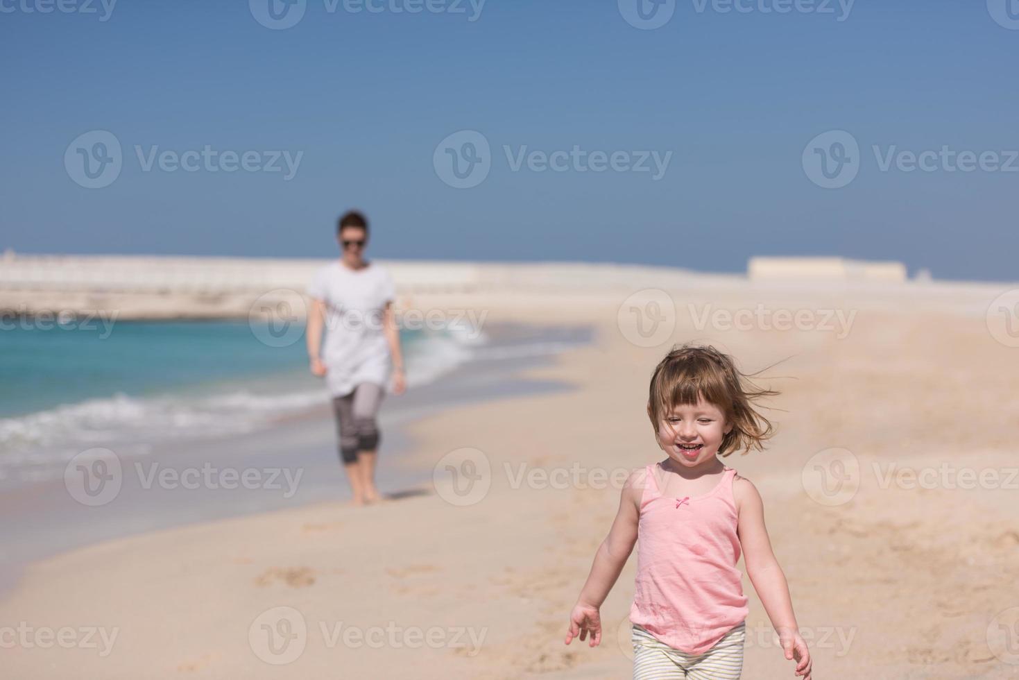 mother and daughter running on the beach photo