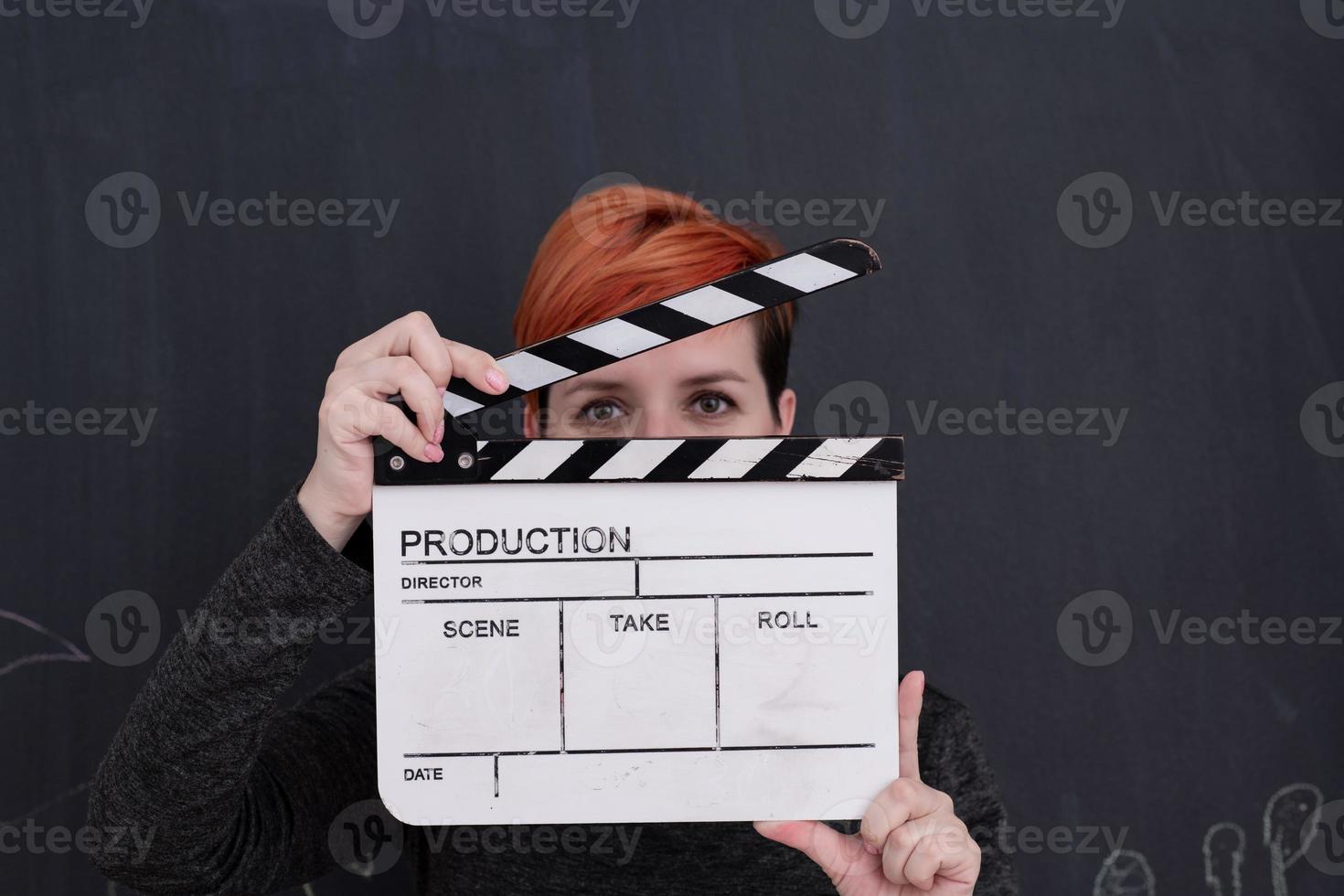 redhead woman holding clapper on black background photo