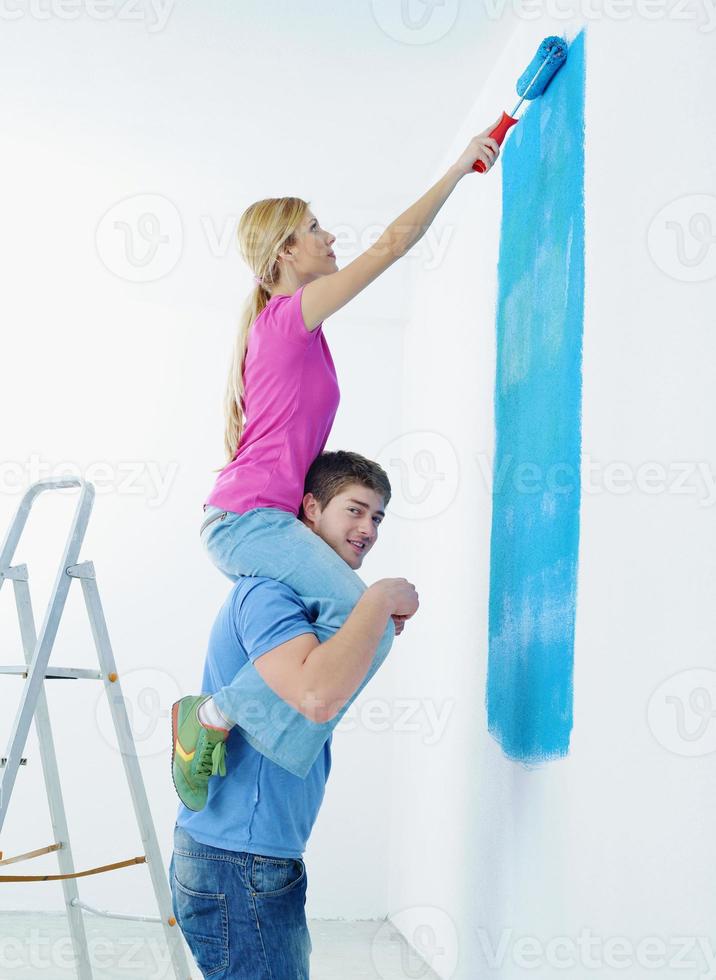 pareja feliz pintando una pared en su nuevo hogar foto