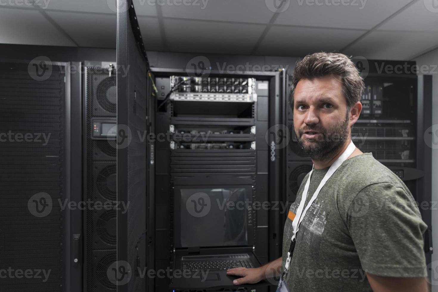 ingeniero del centro de datos que usa el teclado en una instalación especializada en la sala de servidores de supercomputadoras con un administrador de sistemas masculino foto