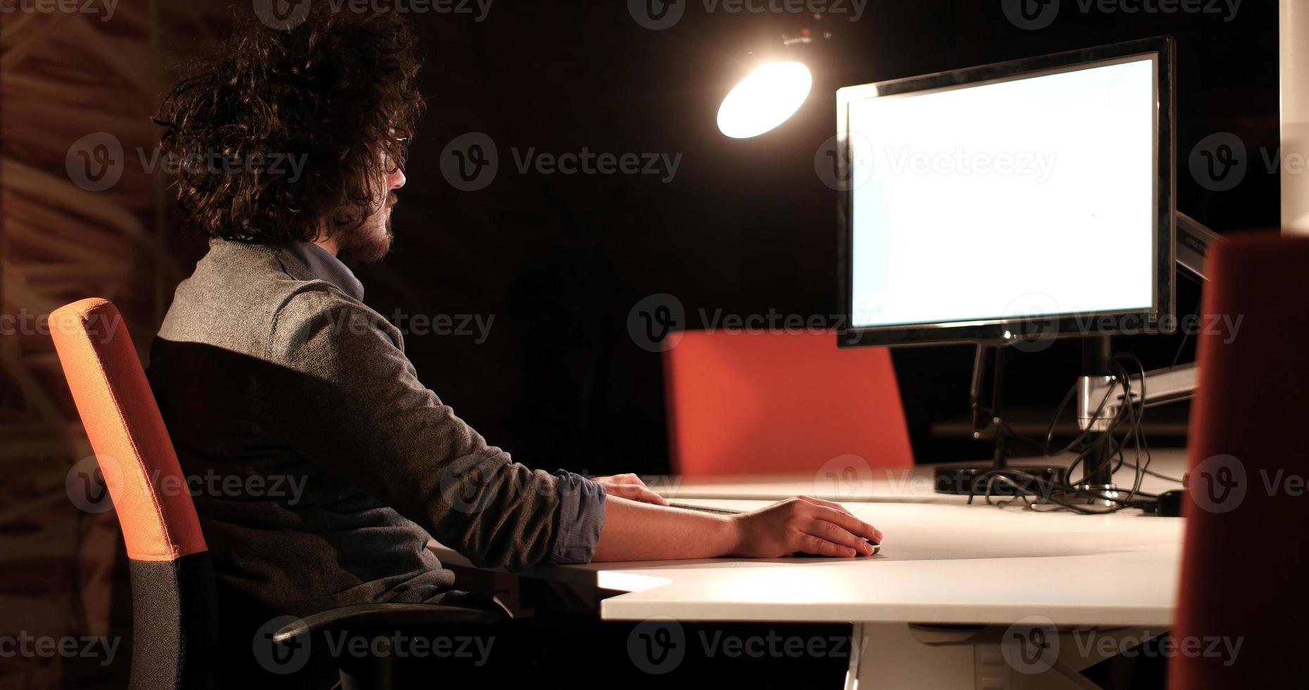 man working on computer in dark office photo
