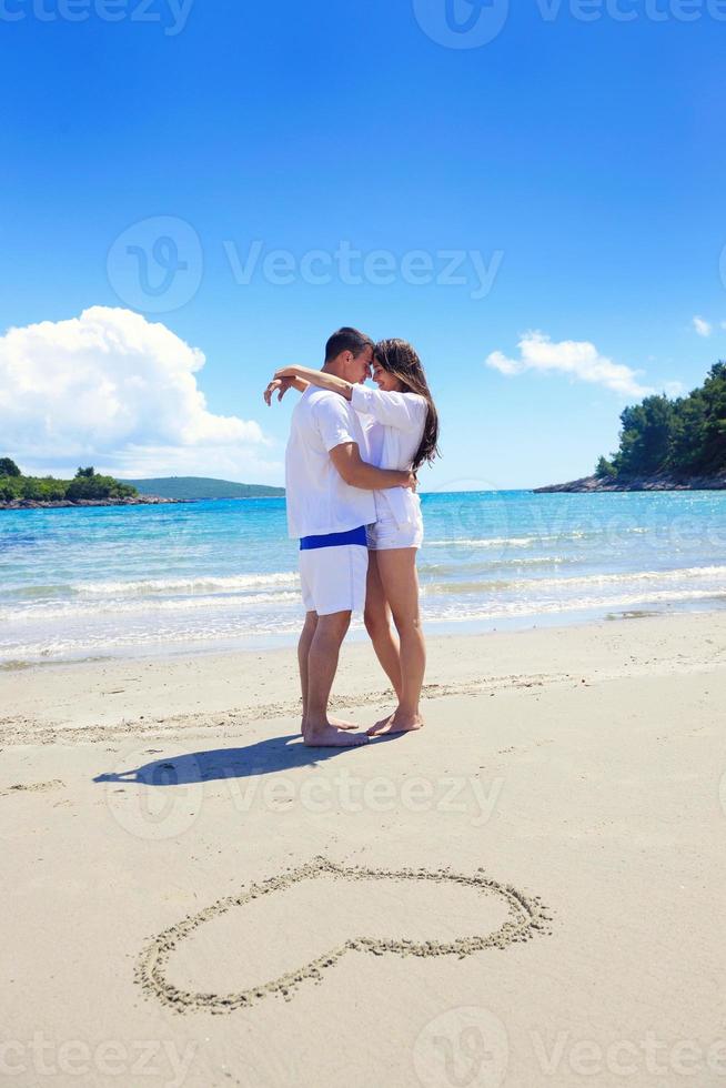 romantic  couple in love  have fun on the beach with heart drawing on sand photo