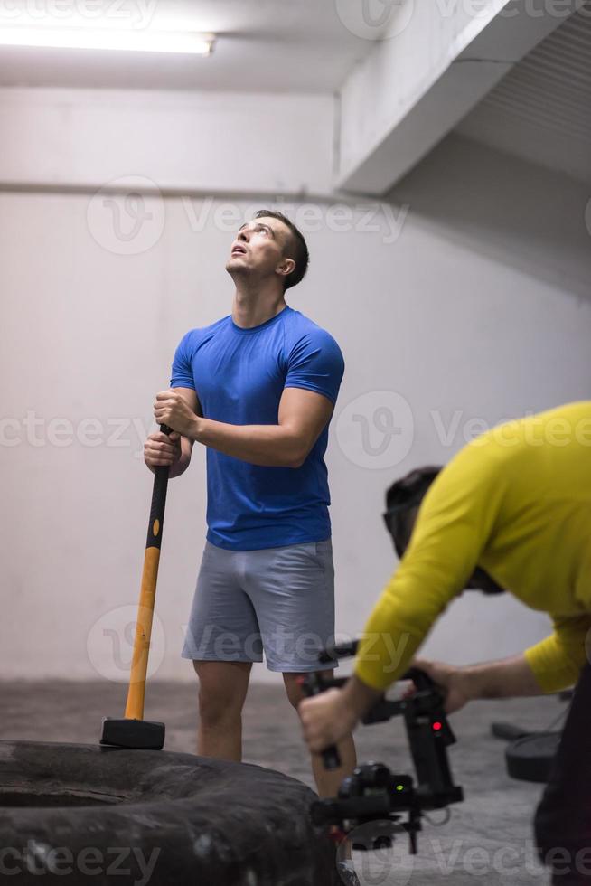 entrenamiento de hombre con martillo y neumático de tractor foto