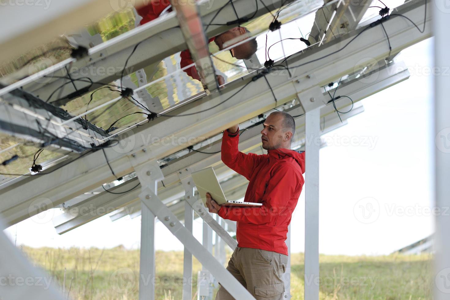 engineer using laptop at solar panels plant field photo