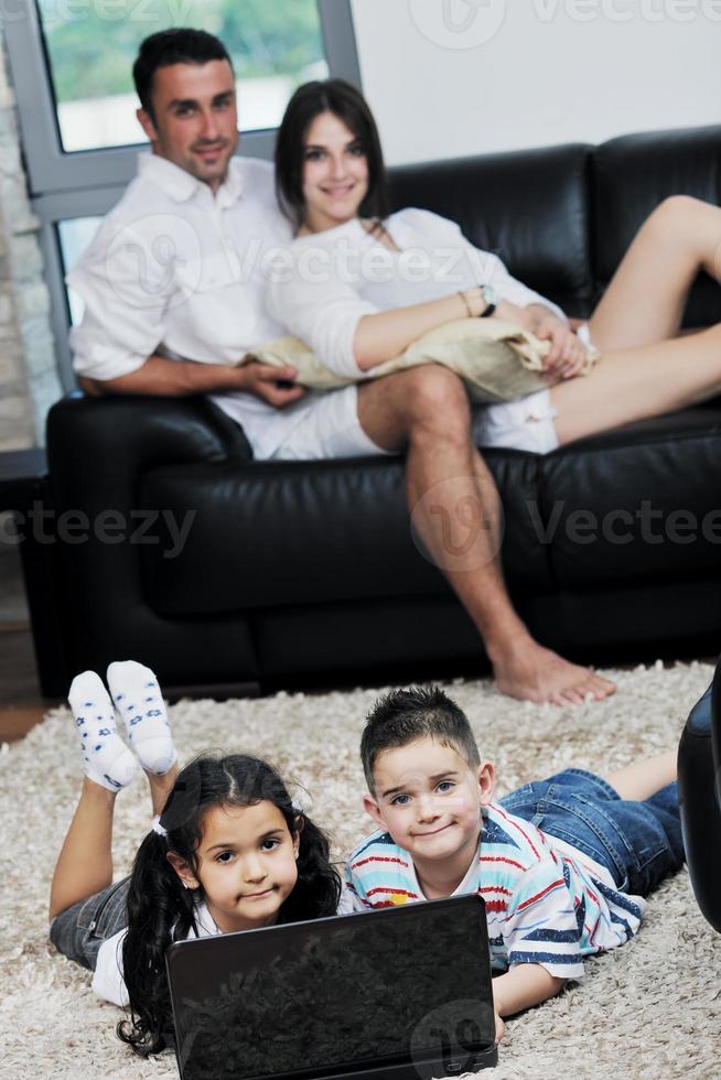 familia joven feliz divertirse y trabajar en la computadora portátil en casa foto