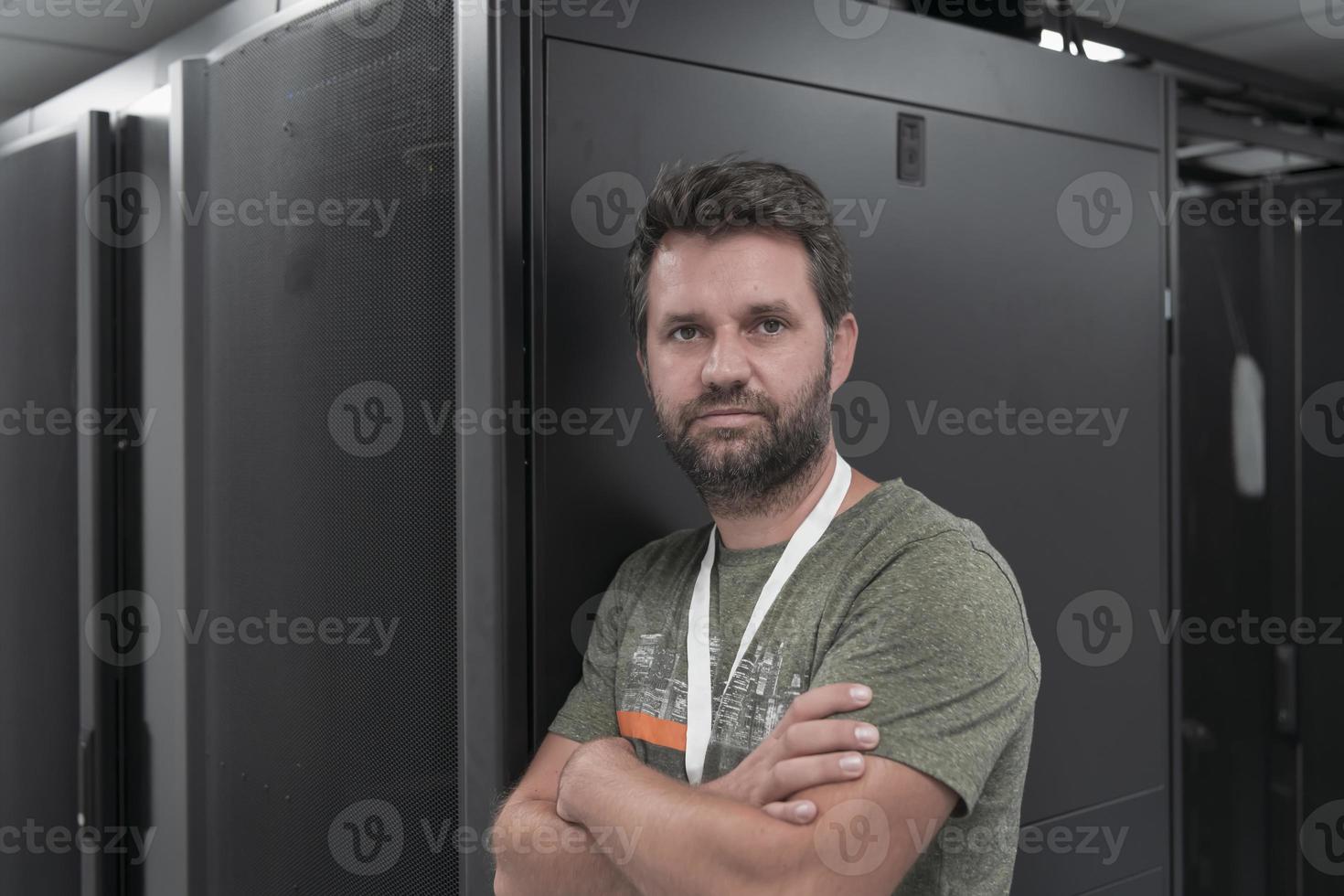 retrato de un técnico o administrador de red masculino que se muestra valiente como un héroe con los brazos cruzados en la sala de servidores del centro de datos. foto