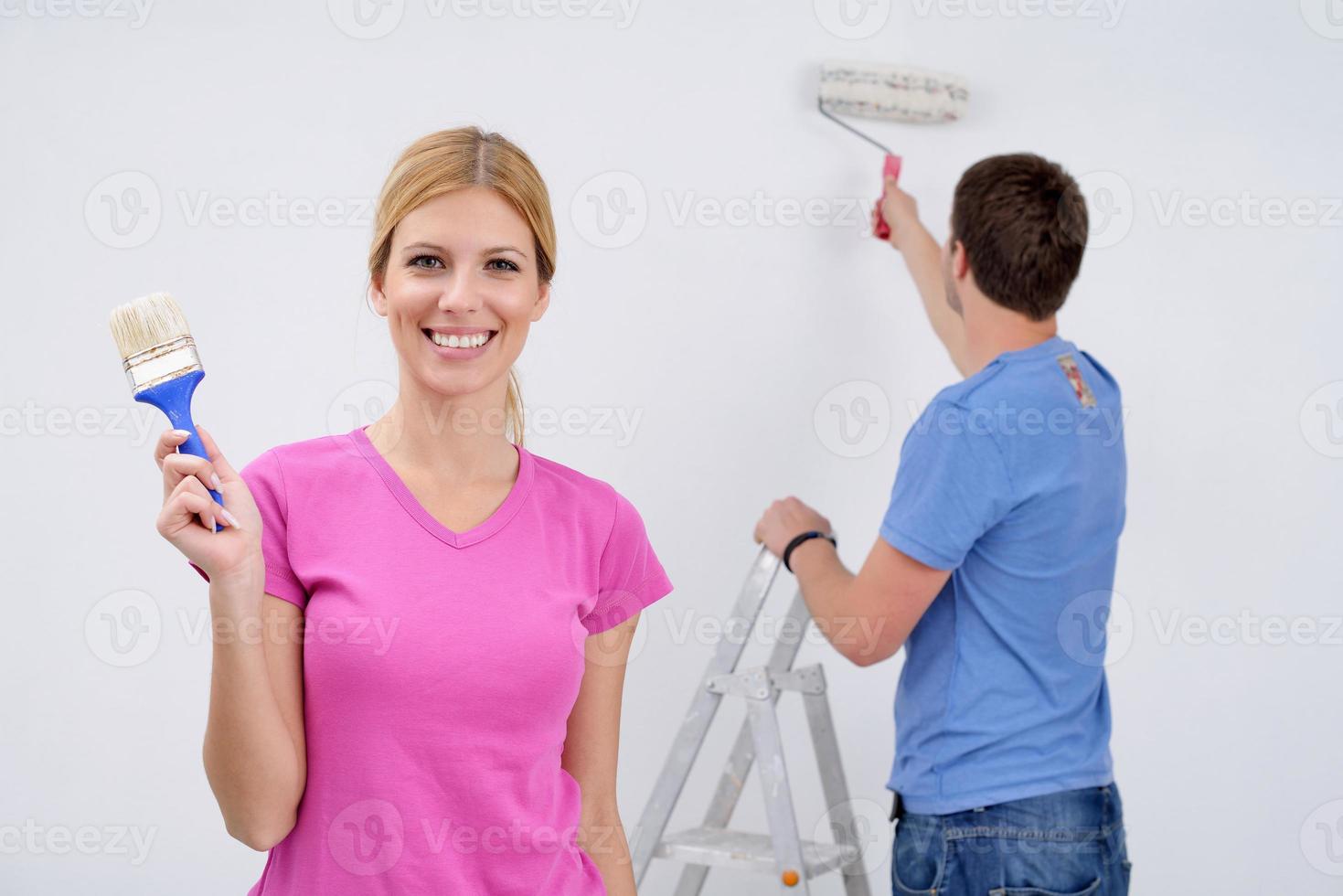 happy couple paint wall at new home photo