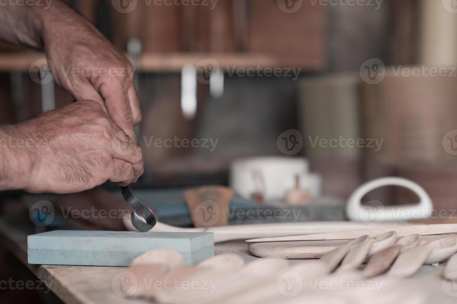 Hands carving spoon from wood, working with chisel close up. Wooden workshop. Process of making wooden spoon photo