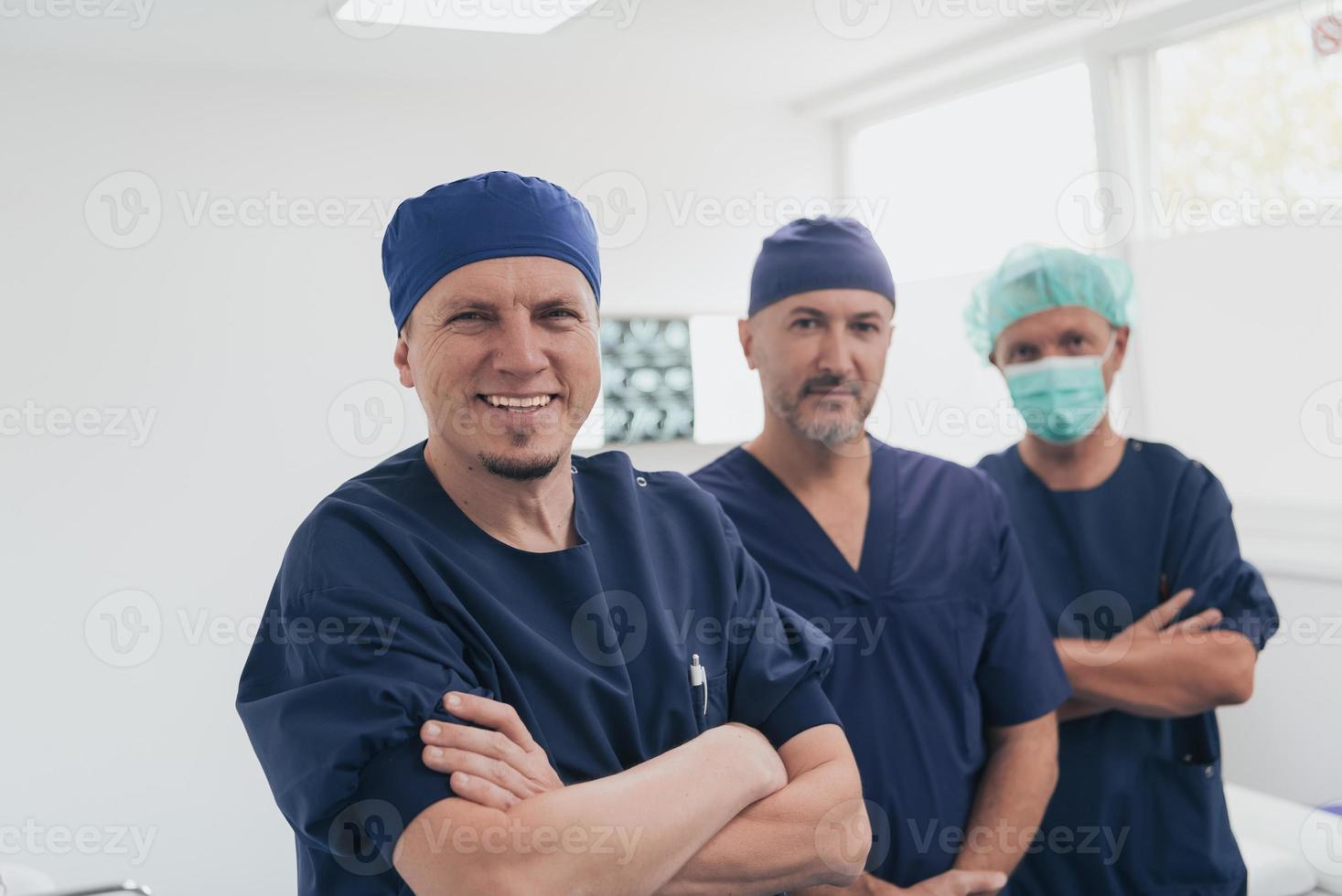 Multiethnic orthopedic doctor in front of his medical team looking at camera wearing face mask photo