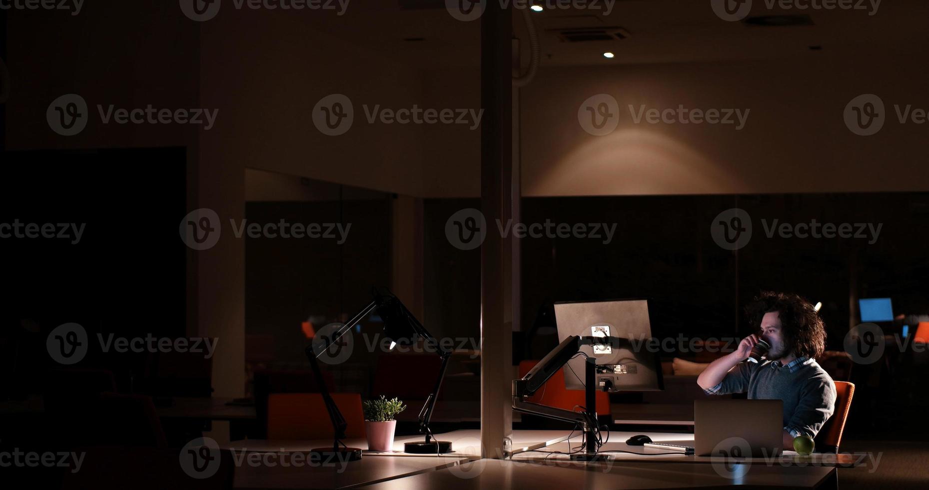 man working on computer in dark office photo