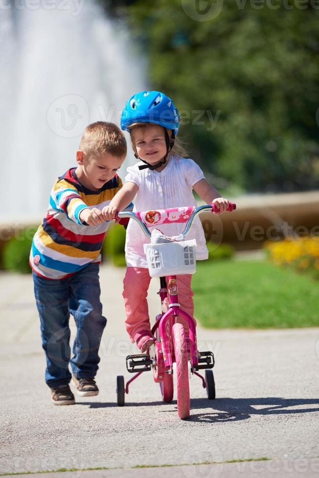 Boy and girl in park learning to ride a bike photo