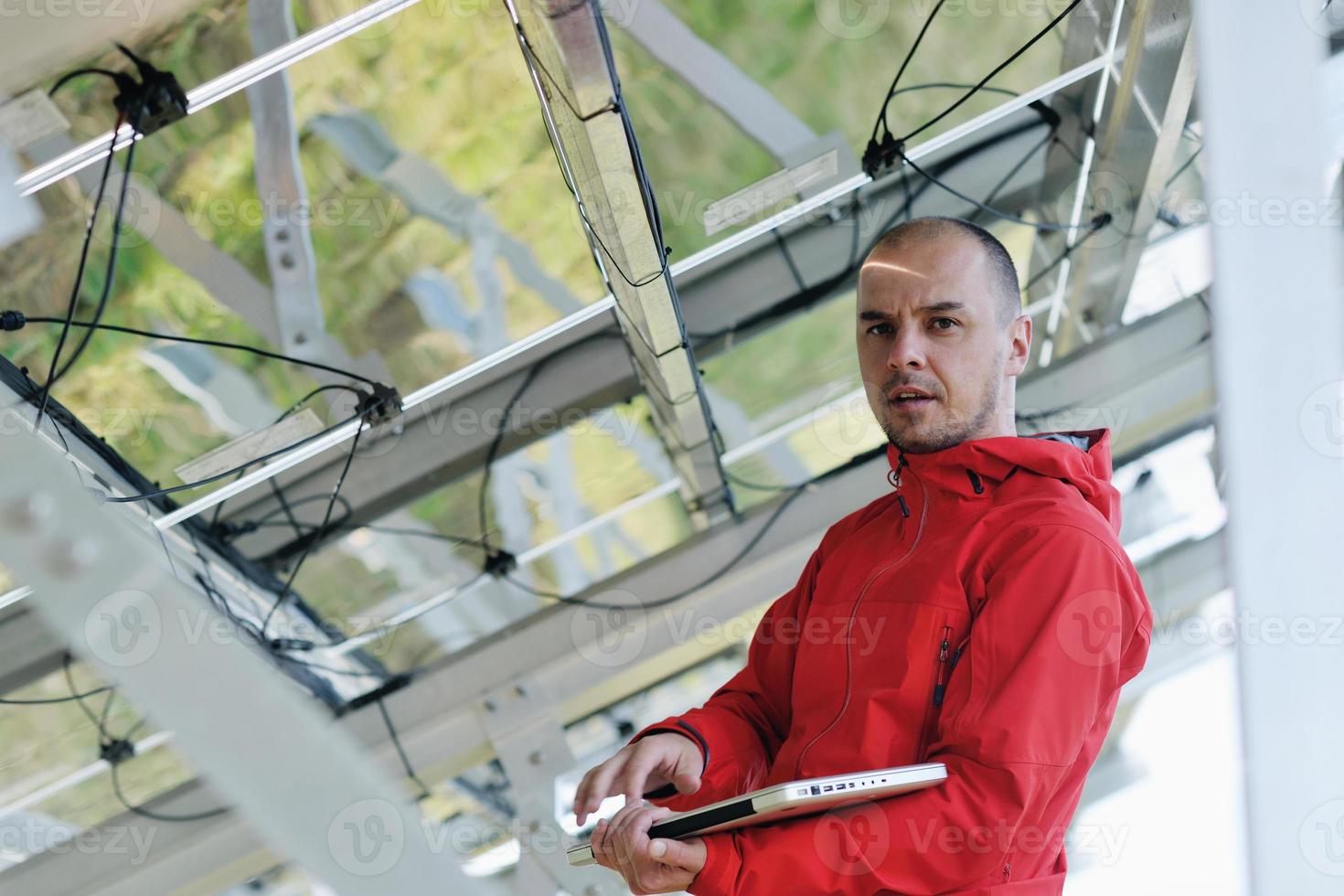 engineer using laptop at solar panels plant field photo