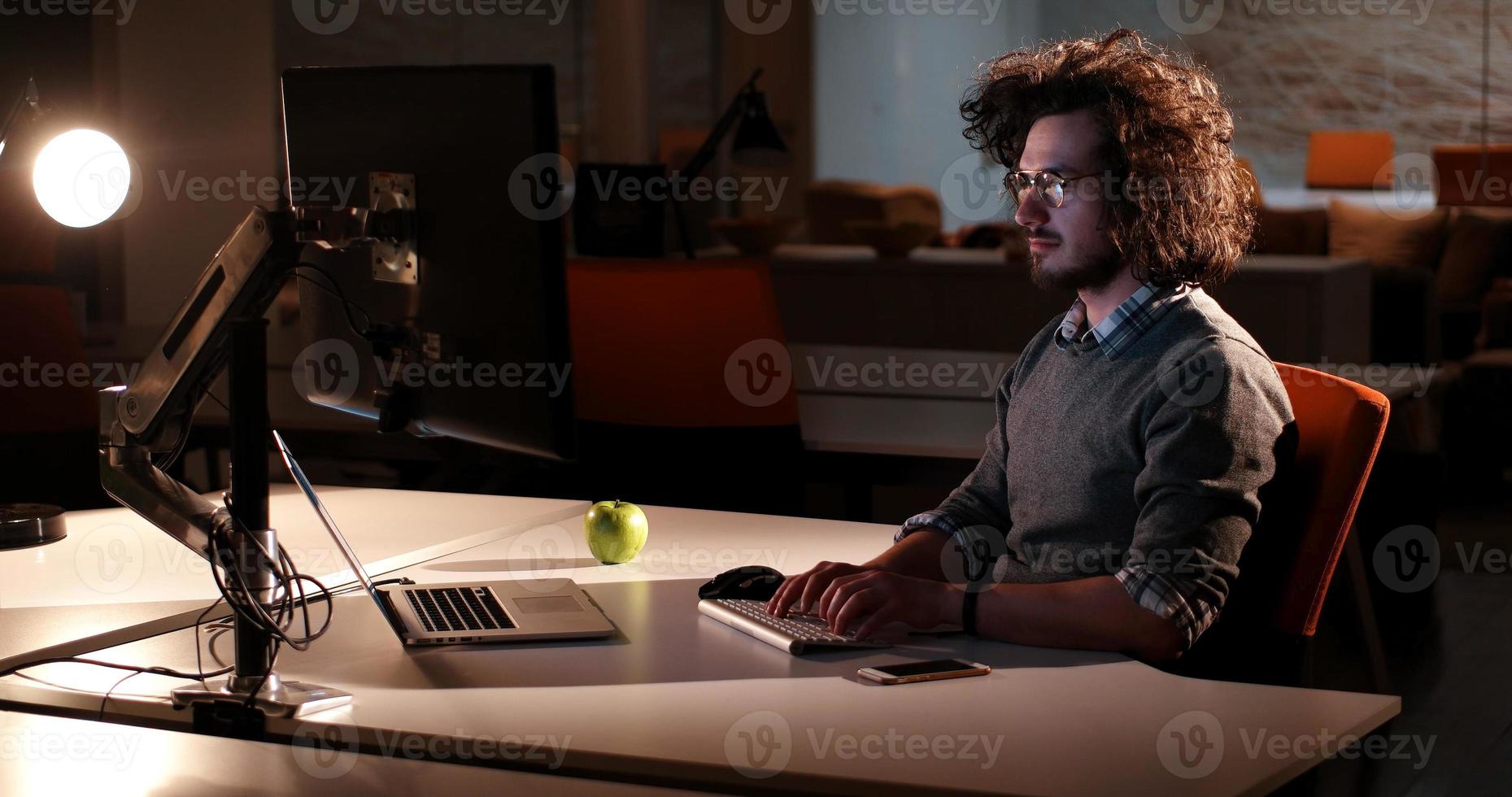 man working on computer in dark office photo