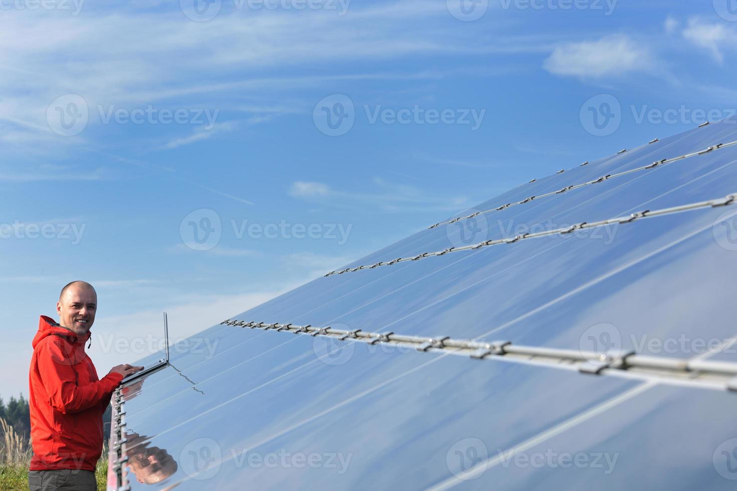 engineer using laptop at solar panels plant field photo