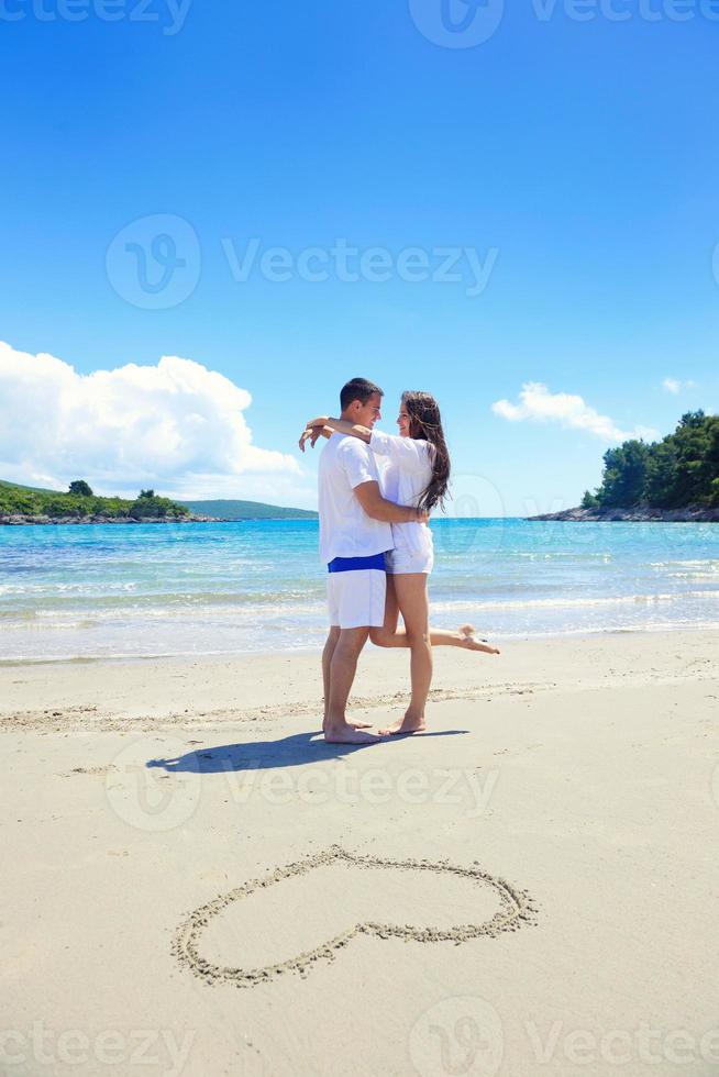 pareja romántica enamorada diviértete en la playa con el corazón dibujando en la arena foto