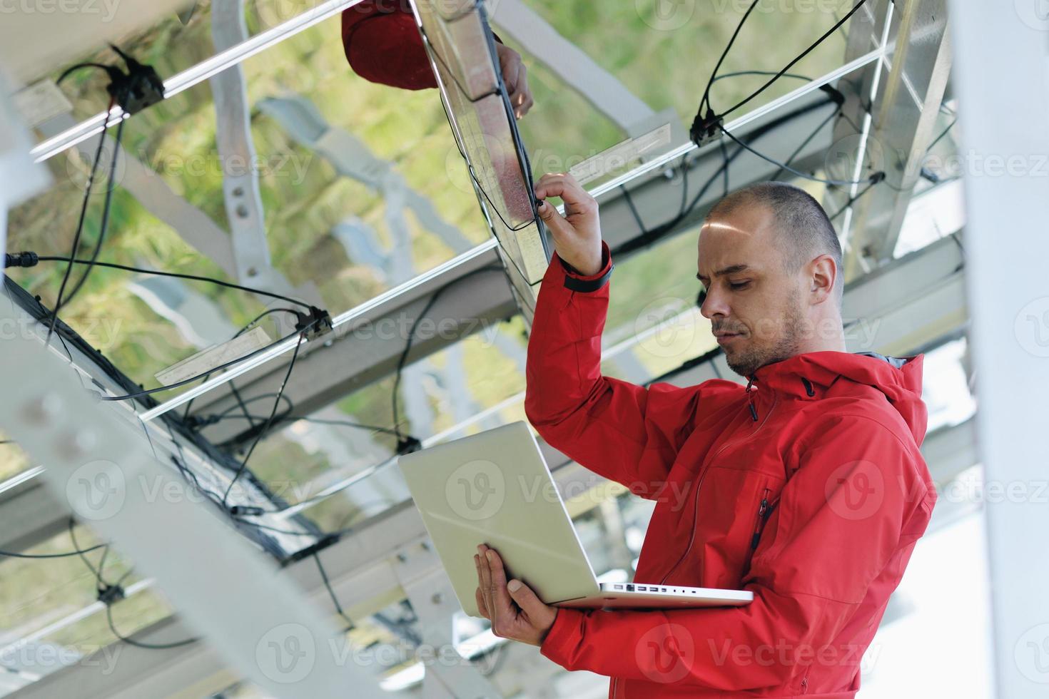 engineer using laptop at solar panels plant field photo